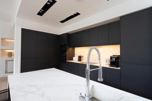 a kitchen with black cabinets and a sink at Marygate - Museum Apartment in York