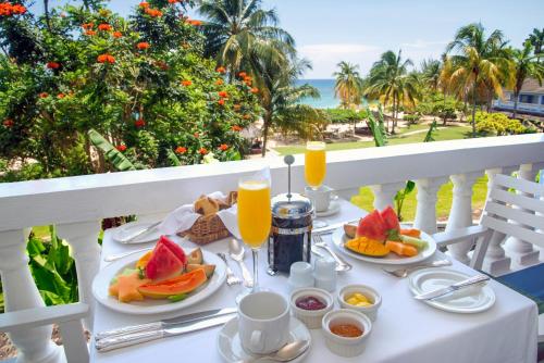 a table with a breakfast of fruit and orange juice at Jamaica Inn in Ocho Rios