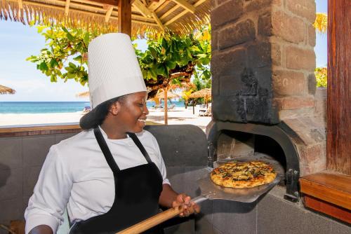 a woman in a chefs hat putting a pizza in an oven at Jamaica Inn in Ocho Rios