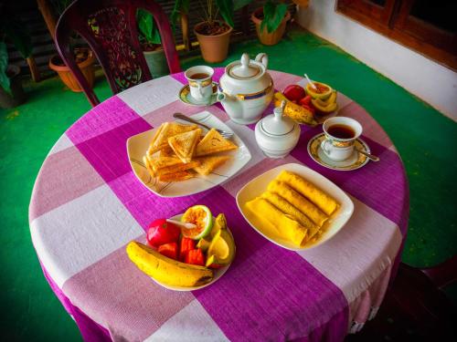 a table with a pink and white table cloth with food on it at Ella Happy View Homestay in Ella