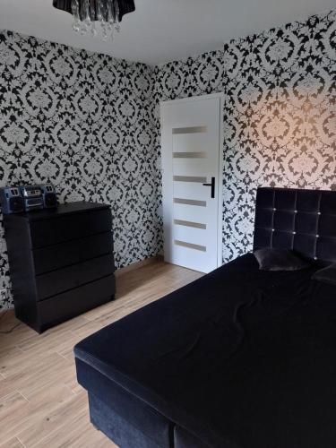 a bedroom with a black bed and a white door at Apartament Chopina 17 in Włocławek
