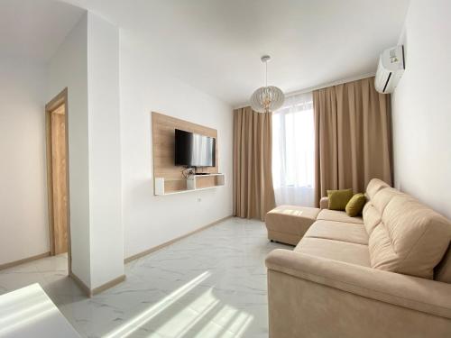 een woonkamer met een bank en een tv bij The Green Paradise Apartments in Primorsko