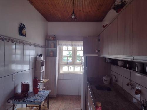 uma cozinha com uma mesa, um frigorífico e uma janela em Sua Casa na Cidade dos Canyons - Cambará do Sul-RS em Cambará