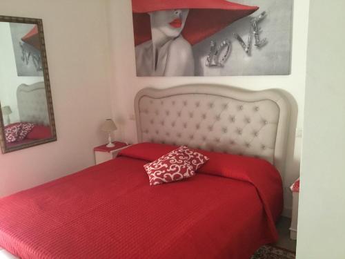 ein rotes Bett mit einer roten Tagesdecke und einem Spiegel in der Unterkunft da Ysabel in Verona