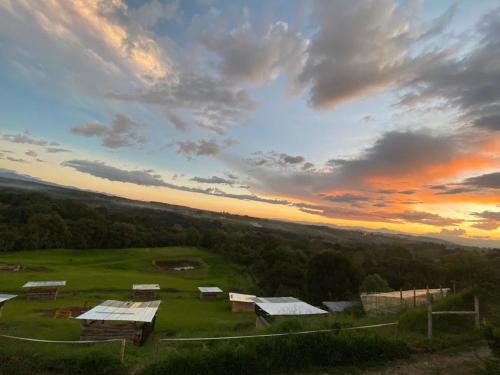 - une vue aérienne sur une ferme avec un coucher de soleil dans l'établissement CAMPING LOS ROBLES POPAYÁN, à Florencia