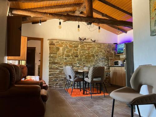ein Wohnzimmer mit einem Tisch, Stühlen und einer Steinmauer in der Unterkunft Quinta da Meda in Coimbra