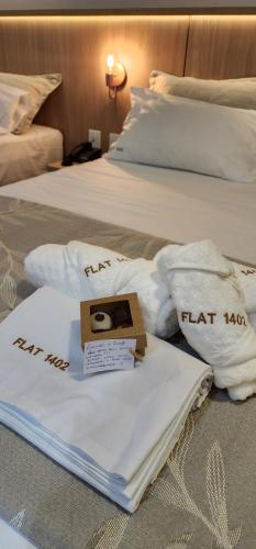 two beds with white towels and a box on them at Flat Maravilhoso na praia - Ilusion Hotel in Natal