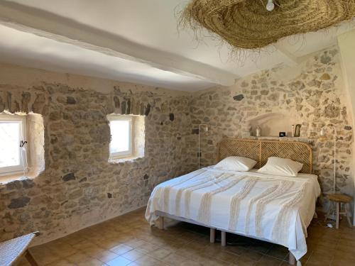 una camera con un letto in una stanza con pareti in pietra di Chambres d'hôtes La Tour d'Aspiran ad Aspiran