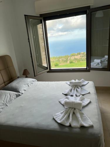 sypialnia z 2 ręcznikami na łóżku z oknem w obiekcie Ville con vista w mieście Drymon