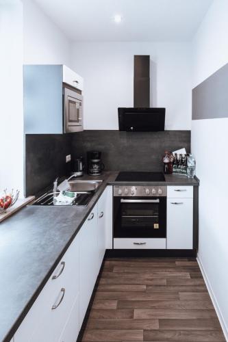 a kitchen with white cabinets and a black counter top at Ferienwohnung Goitzschezeit in Bitterfeld