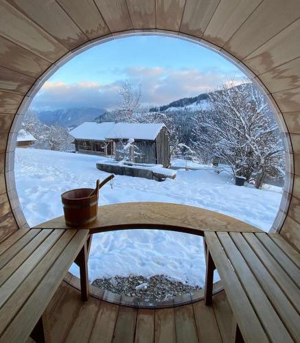a round window in a cabin with a snow covered yard at Luxury Chalet, stunning views with hot tub & sauna in La Côte dʼArbroz