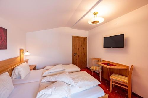 a room with two beds and a desk and a television at Rustika - Appartements & Spa in Ehrwald