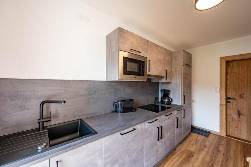 a kitchen with a sink and a microwave at Rustika - Appartements & Spa in Ehrwald