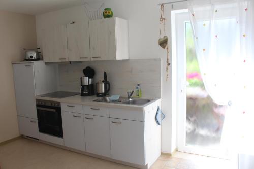 una cucina bianca con lavandino e piano cottura di Basislager Hohnstein - Familie Lösel a Ehrenberg