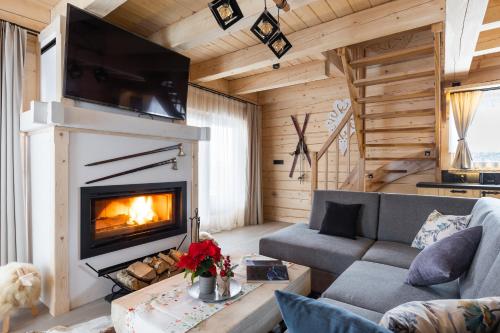a living room with a fireplace in a log cabin at Osada Chłabówka Zakopane & SPA in Zakopane