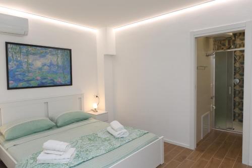 a white bedroom with a bed with towels on it at Piccina House in Cefalù