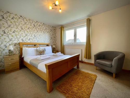 a bedroom with a bed and a chair at Allanvale Holiday Home in Inverness