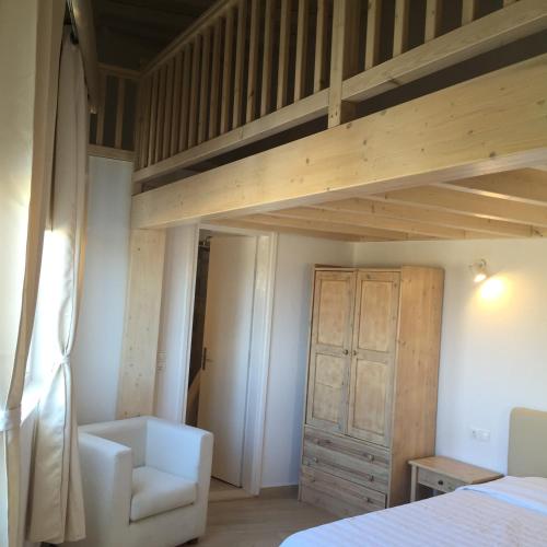 a bedroom with a loft bed and a chair at Paolas Sunset in Agios Stefanos