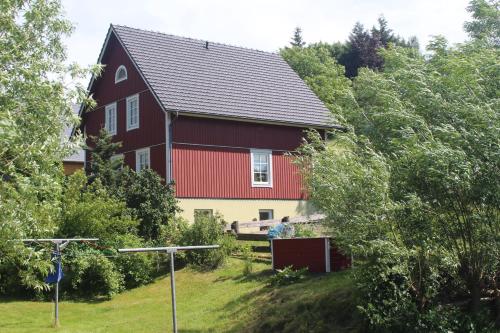 een rood huis in het midden van een veld bij Basislager Hohnstein - Familie Lösel in Ehrenberg
