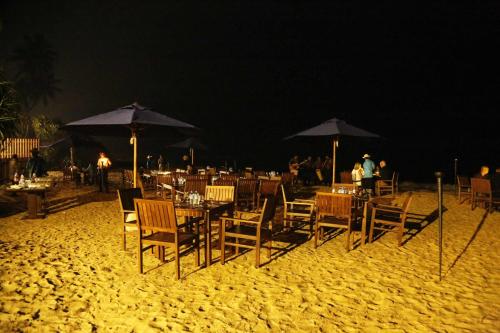 a group of tables and chairs on a beach at night at Blue Beach Hotel in Wadduwa