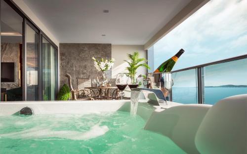 a bath tub with a bottle of wine and a glass at The Elysium Prațumnak Pattaya - By SHG in Pattaya South