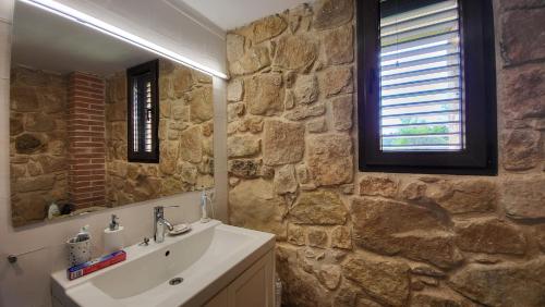 baño con lavabo y pared de piedra en Mas De La Font, en Lledó