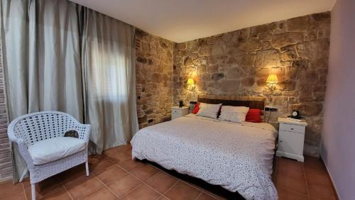 1 dormitorio con cama y pared de piedra en Mas De La Font en Lledó