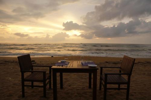 a table and chairs on the beach with the ocean at Blue Beach Hotel in Wadduwa