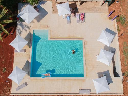 een uitzicht over een zwembad met witte parasols bij Masseria Serine in Leuca
