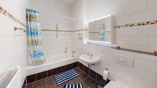 y baño blanco con lavabo y bañera. en SweetHome - Business-Apartment mit Küche, Terrasse, Stellplatz, en Magdeburgo