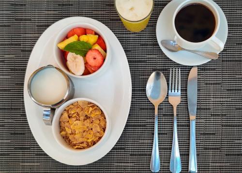 a plate with two bowls of fruit and a cup of coffee at Hotel Giada in Sámara
