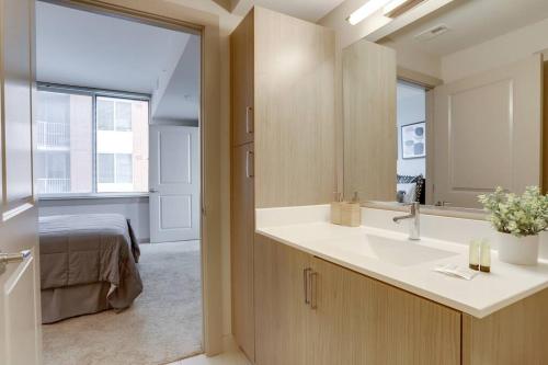 a bathroom with a sink and a bed in a room at Stylish Condo at Crystal City With Rooftop in Arlington