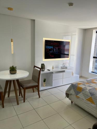 a white living room with a table and a tv at Suíte luxo com tela de cinema no América Towers Studio Residence in Salvador