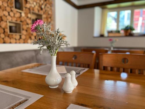 two white vases with flowers on a wooden table at Hotel Weisses Rössli in Göschenen