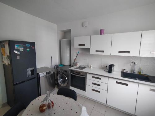 - une cuisine avec des placards blancs, une table et un lave-vaisselle dans l'établissement Bel Appartement 3 étoiles 6 pers 3 pièces 60m2 idéalement placé, à Cabourg