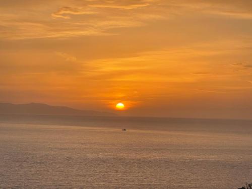 a sunset over the ocean with a boat in the water at Paolas Sunset in Agios Stefanos