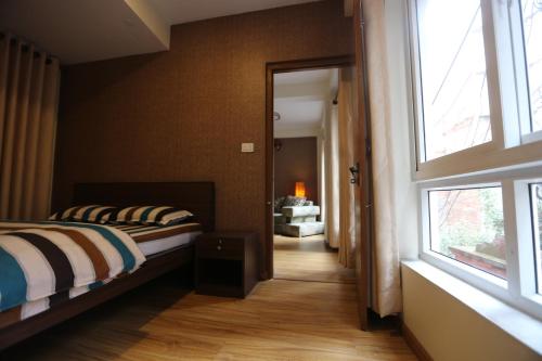Un dormitorio con una cama y una ventana grande. en NhuChhe Apartments, en Pātan
