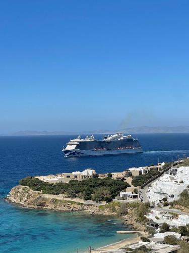 a cruise ship in the ocean next to a small island at Paolas Sunset in Agios Stefanos