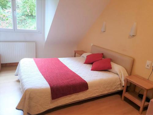 - une chambre avec un grand lit et des oreillers rouges dans l'établissement L'Orée du Bois, à Ergué-Gabéric
