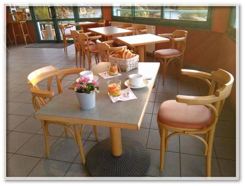 un restaurant avec des tables, des chaises et des fleurs. dans l'établissement L'Orée du Bois, à Ergué-Gabéric