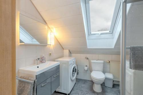 bagno con lavandino, servizi igienici e finestra. di Ferienhaus Anne mit Sauna, See, Wald und Ruhe a Kirchheim