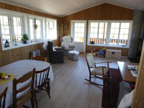 uma sala de estar com uma mesa, cadeiras e janelas em Ny hytte i flott turterreng 