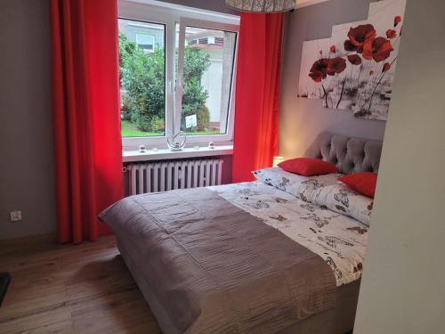 Schlafzimmer mit einem Bett mit roten Vorhängen und einem Fenster in der Unterkunft Apertament JOWISZ in Zabrze
