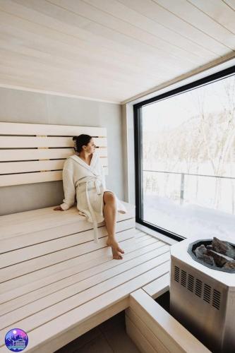 a woman sitting in the inside of a sauna at Chalet Flodhaus- Bord Rivière St-Maurice (navigable) / SPA /SAUNA - Chalets Galaxia in Saint Roch de Mekinac