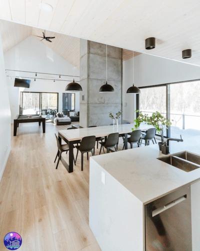 a kitchen and living room with a table and chairs at Chalet Flodhaus- Bord Rivière St-Maurice (navigable) / SPA /SAUNA - Chalets Galaxia in Saint Roch de Mekinac