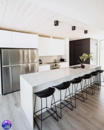 a kitchen with a large white counter with bar stools at Chalet Flodhaus- Bord Rivière St-Maurice (navigable) / SPA /SAUNA - Chalets Galaxia in Saint Roch de Mekinac