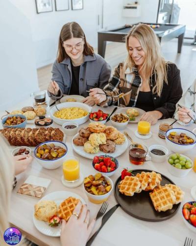 a group of women sitting around a table with food at Chalet Flodhaus- Bord Rivière St-Maurice (navigable) / SPA /SAUNA - Chalets Galaxia in Saint Roch de Mekinac