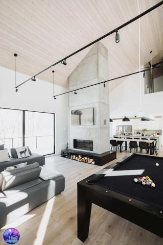 a living room with a pool table and a fireplace at Chalet Flodhaus- Bord Rivière St-Maurice (navigable) / SPA /SAUNA - Chalets Galaxia in Saint Roch de Mekinac