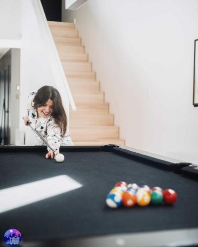 a young girl playing pool on a pool table at Chalet Flodhaus- Bord Rivière St-Maurice (navigable) / SPA /SAUNA - Chalets Galaxia in Saint Roch de Mekinac