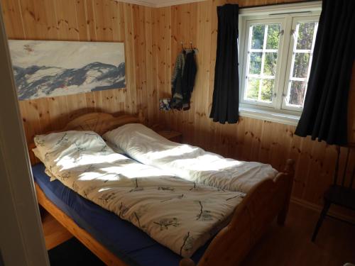 een bed in een houten kamer met een raam bij Ny hytte i flott turterreng 